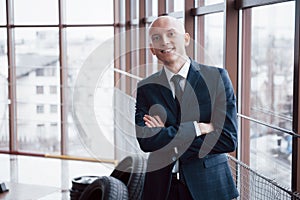 Portrait of smiling young businessman standing arms crossed leaning on cupboard in office