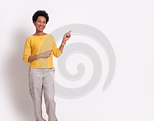 Portrait of smiling young businesswoman with afro hair pointing at copy space on white background