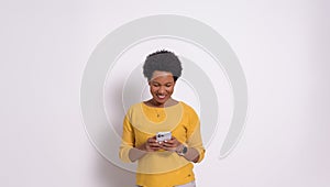 Portrait of smiling young businesswoman with afro hair texting over smart phone on white background