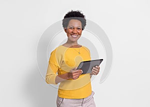 Portrait of smiling young businesswoman holding digital tablet and standing over white background