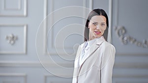 Portrait of smiling young businesswoman posing and looking at camera in white luxury background