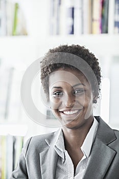Portrait of smiling young businesswoman with short hair looking at the camera, head and shoulders