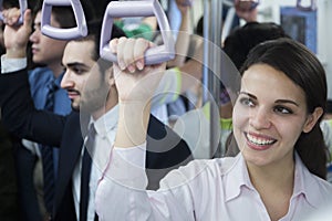 Portrait of smiling young businesswoman standing on the subway, looking away