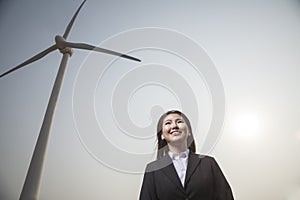 Portrait of smiling young businesswoman standing by a wind turbine