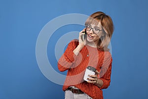 Portrait of a smiling young casual woman talking on mobile phone isolated over blue background