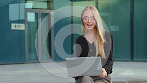 Portrait of smiling young Caucasian female employee in glasses work outdoor. Happy millennial woman worker waving hand