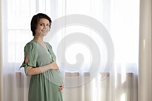 Portrait of smiling pregnant woman caress belly bump photo