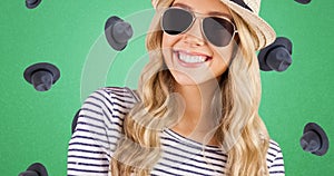 Portrait of smiling young caucasian woman wearing sunglasses and hat, headwear on green background