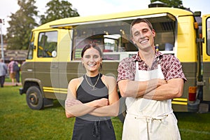 Portrait Of Smiling Young Couple In Front Of Food Catering Van At Summer Music Festival