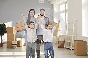 Portrait of smiling young couple with little kids in their new home on moving day