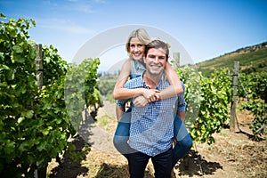 Portrait of smiling young couple piggybacking at vineyard