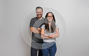 Portrait of smiling young couple wearing eyeglasses and casuals standing confidently against background. Joyful handsome man and