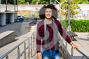 Portrait of a smiling young curly haired latin man walking up a ramp