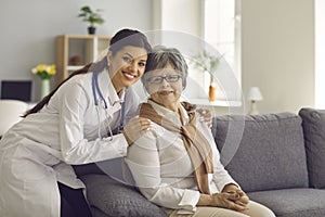 Portrait of smiling young doctor or home care nurse embracing her senior patient
