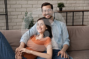 Portrait of smiling young family couple relaxing on sofa.