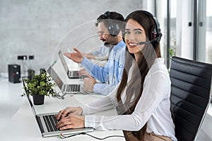 Portrait of smiling young female call center operator wearing headphones working in customer support service