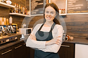 Portrait of smiling young female coffee shop owner, confident woman with arms crossed standing at the counter