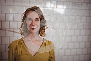 Portrait of smiling young female customer standing against white wall