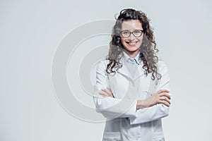 Portrait of smiling young female doctor. Beautiful brunette in white medical gown in glasses. Holding without a