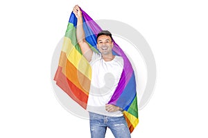 Portrait of a smiling young gay man holding a lgbtqi flag on a white background.