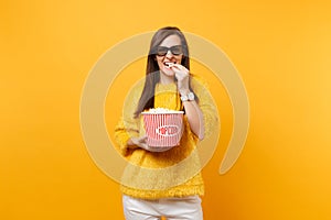 Portrait of smiling young girl in 3d imax glasses watching movie film, eating popcorn from bucket isolated on bright