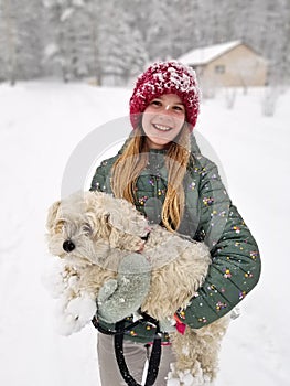 Portrait of A Smiling young girl holding up her Extremely Shaggy Dog Whose Paws are Caked in Snow