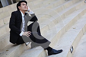 Portrait of smiling young handsome businessman sitting on the stairs