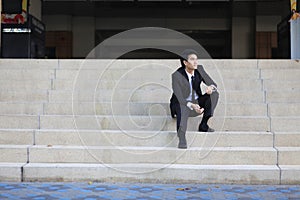 Portrait of smiling young handsome businessman sitting on the stairs