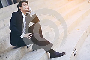 Portrait of smiling young handsome businessman sitting on the stairs