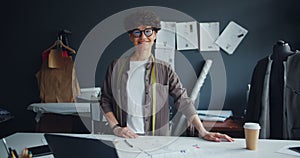 Portrait of smiling young lady seamstress looking at camera standing in studio