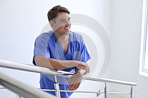 Portrait Of Smiling Young Male Doctor Or Nurse Standing On Stairs In Hospital