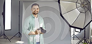 Portrait of smiling young male photographer with his camera at work in photo studio