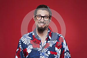 Portrait of a smiling young man in Hawaiian shirt against red ba