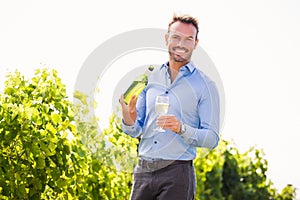 Portrait of smiling young man holding wine bottle and glass