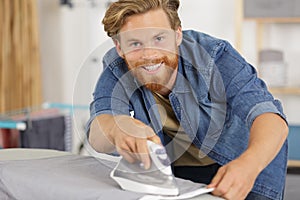 portrait smiling young man ironing cloth