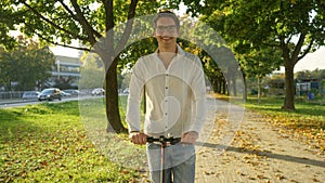 PORTRAIT: Smiling young man looks into the camera while riding an e-scooter.