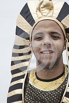 Portrait of smiling young man wearing a headdress from ancient Egypt, studio shot