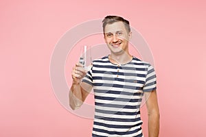 Portrait of smiling young man wearing striped t-shirt holding and drinking clear fresh pure water from glass isolated on
