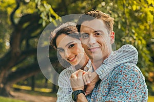 Portrait smiling young man and woman couple in love hugging in the park at summer season with warm sunlight. people and lifestyle