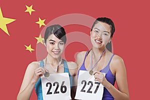 Portrait of smiling young medalists standing against Chinese flag