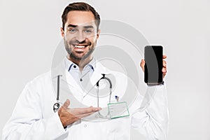 Portrait of smiling young medical doctor with stethoscope working in clinic and holding cellphone