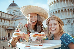 Portrait of smiling young mother and daughter with pizza