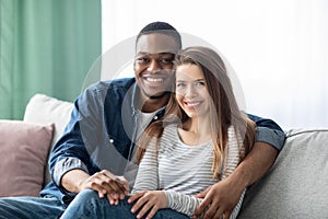 Portrait Of Smiling Young Multicultural Couple Posing In Home Interior
