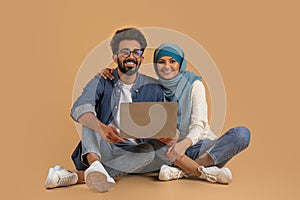 Portrait Of Smiling Young Muslim Couple Using Laptop Computer Together