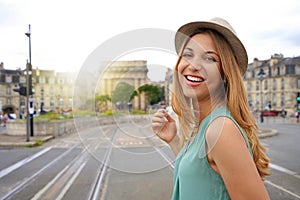 Portrait of smiling young tourist woman looks at camera on Pont de pierre bridge in Bordeaux, France