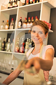 Portrait of smiling young waitress giving customer change while standing at counter in restaurant