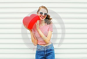 Portrait smiling young woman with air balloons heart shape having fun over white