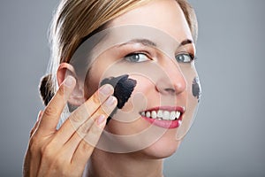 Woman Applying Activated Charcoal Mask On Her Face photo