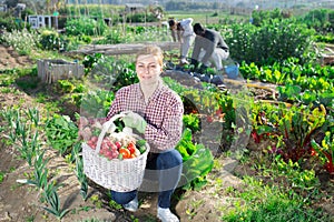 Portrait of a smiling young woman with a basket of harvested crops