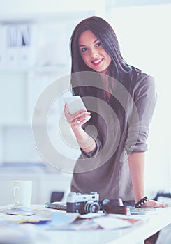 Portrait of smiling young woman with camera sitting in loft apartment